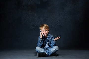 Image showing Little boy sitting with smartphone in studio