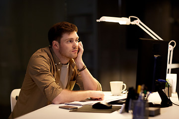 Image showing tired or bored man on table at night office