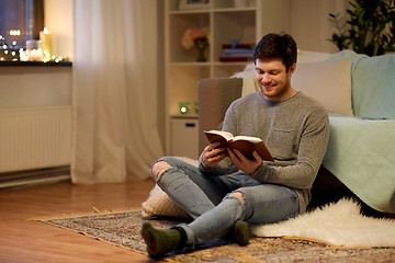 Image showing happy young man reading book at home