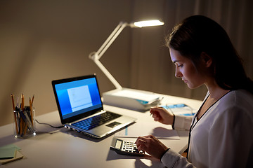 Image showing woman with calculator and papers at night office