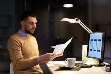 Image showing man with papers and computer works at night office