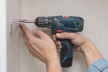 Image showing The master screws the furniture corner to the cabinet with a screwdriver, close-up