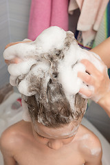 Image showing Mum soaps the baby\'s long hair with shampoo