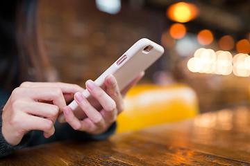 Image showing Woman texting on mobile phone in coffee shop