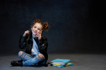 Image showing Little girl sitting with smartphone in studio