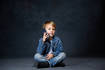 Image showing Little boy sitting with smartphone in studio