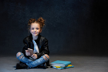 Image showing Little girl sitting with smartphone in studio