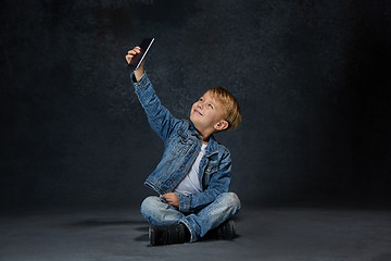 Image showing Little boy sitting with smartphone in studio