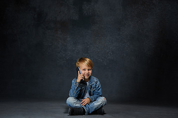 Image showing Little boy sitting with smartphone in studio