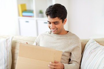 Image showing happy man opening parcel box at home