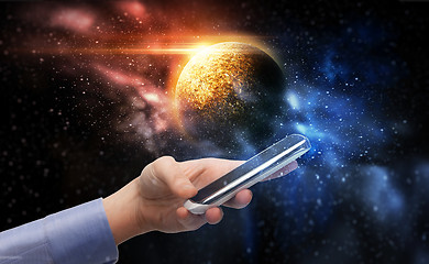 Image showing hand holding smartphone over planet in space