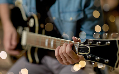 Image showing close up of man playing guitar at studio rehearsal