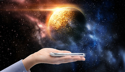 Image showing hand holding smartphone over planet in space