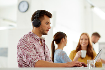 Image showing creative man in headphones with laptop at office