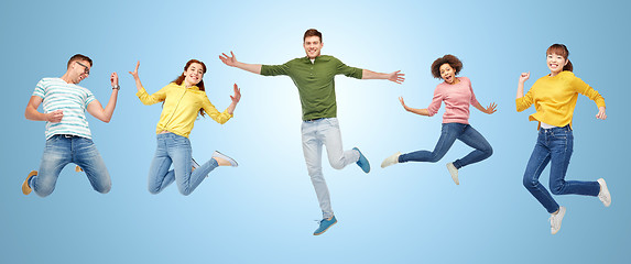 Image showing happy people or friends jumping in air over blue