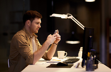 Image showing man with smartphone working late at night office