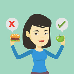 Image showing Woman choosing between hamburger and cupcake.