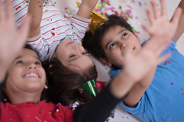 Image showing kids  blowing confetti while lying on the floor