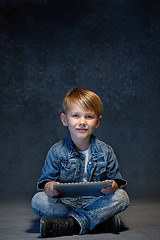 Image showing Little boy sitting with tablet in studio