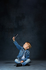 Image showing Little boy sitting with smartphone in studio