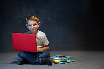 Image showing Little boy sitting with laptop in studio