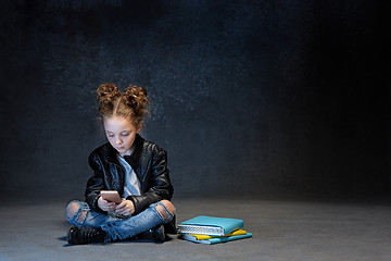 Image showing Little girl sitting with smartphone in studio