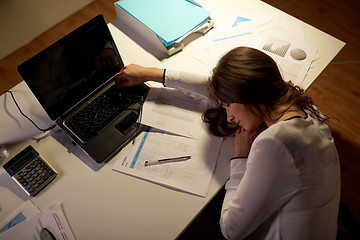 Image showing tired woman sleeping on office table at night