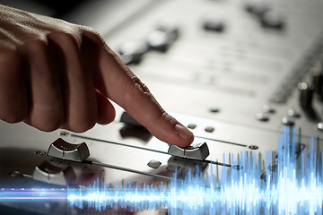 Image showing hand using mixing console for music recording