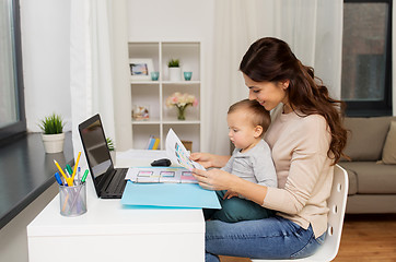 Image showing mother with baby and documents working at home