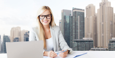 Image showing businesswoman with notepad and laptop at office