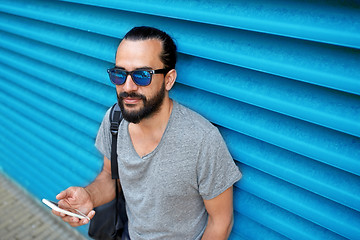 Image showing man in sunglasses with smartphone and bag at wall