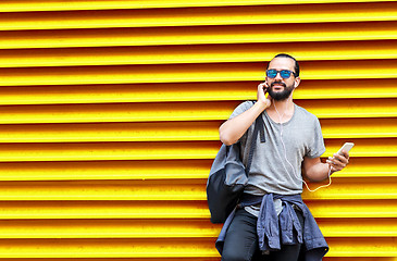 Image showing man with earphones and smartphone over wall