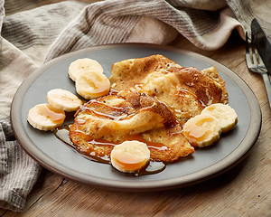 Image showing Crepes with banana and caramel sauce on wooden desk