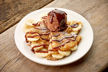 Image showing Crepes with banana and chocolat icecream on wooden desk