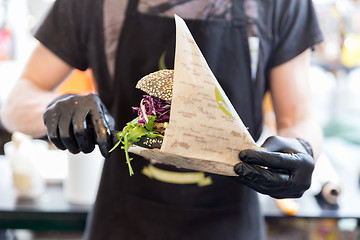 Image showing Chef serving organic vegetarian fish burger at international urban street food festival.