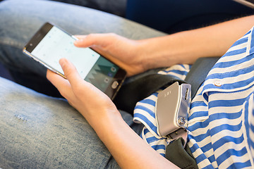 Image showing Female passenger with seat belt fastened switching mobile phone to flight mode while sitting on airplane for safe flight.