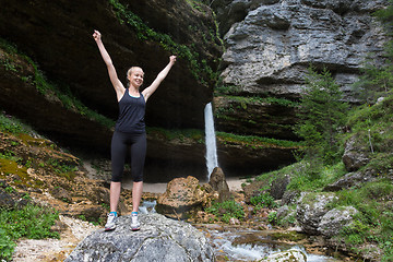 Image showing Active woman raising arms inhaling fresh air, feeling relaxed in nature.