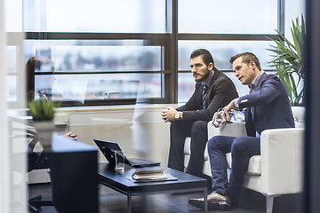 Image showing Businessmen interviewing female candidate for job in modern corporate office.