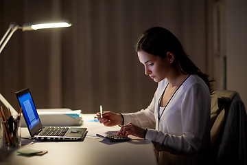 Image showing woman with calculator and papers at night office