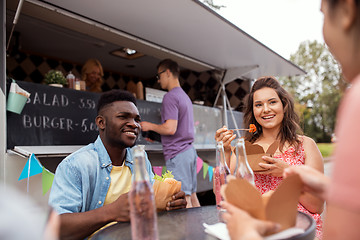 Image showing happy friends with drinks eating at food truck