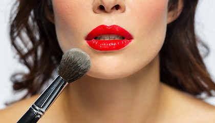 Image showing face of woman with red lipstick applying powder