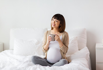 Image showing happy pregnant woman with cup drinking tea at home