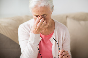 Image showing senior woman with glasses having headache at home