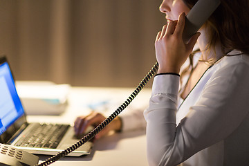 Image showing woman with laptop calling on phone at night office