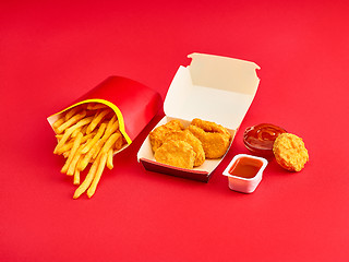 Image showing chicken nuggets and french fries on red background