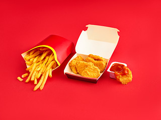 Image showing chicken nuggets and french fries on red background