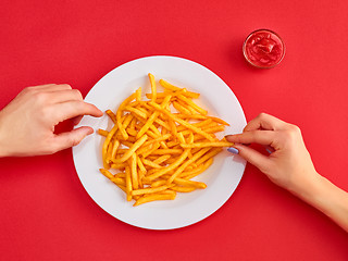 Image showing Young woman eating french fries potato with ketchup in a restaurant