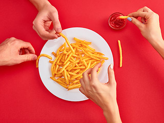 Image showing Young woman eating french fries potato with ketchup in a restaurant