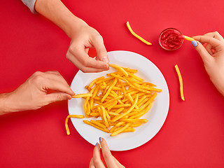 Image showing Young woman eating french fries potato with ketchup in a restaurant