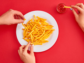 Image showing Young woman eating french fries potato with ketchup in a restaurant